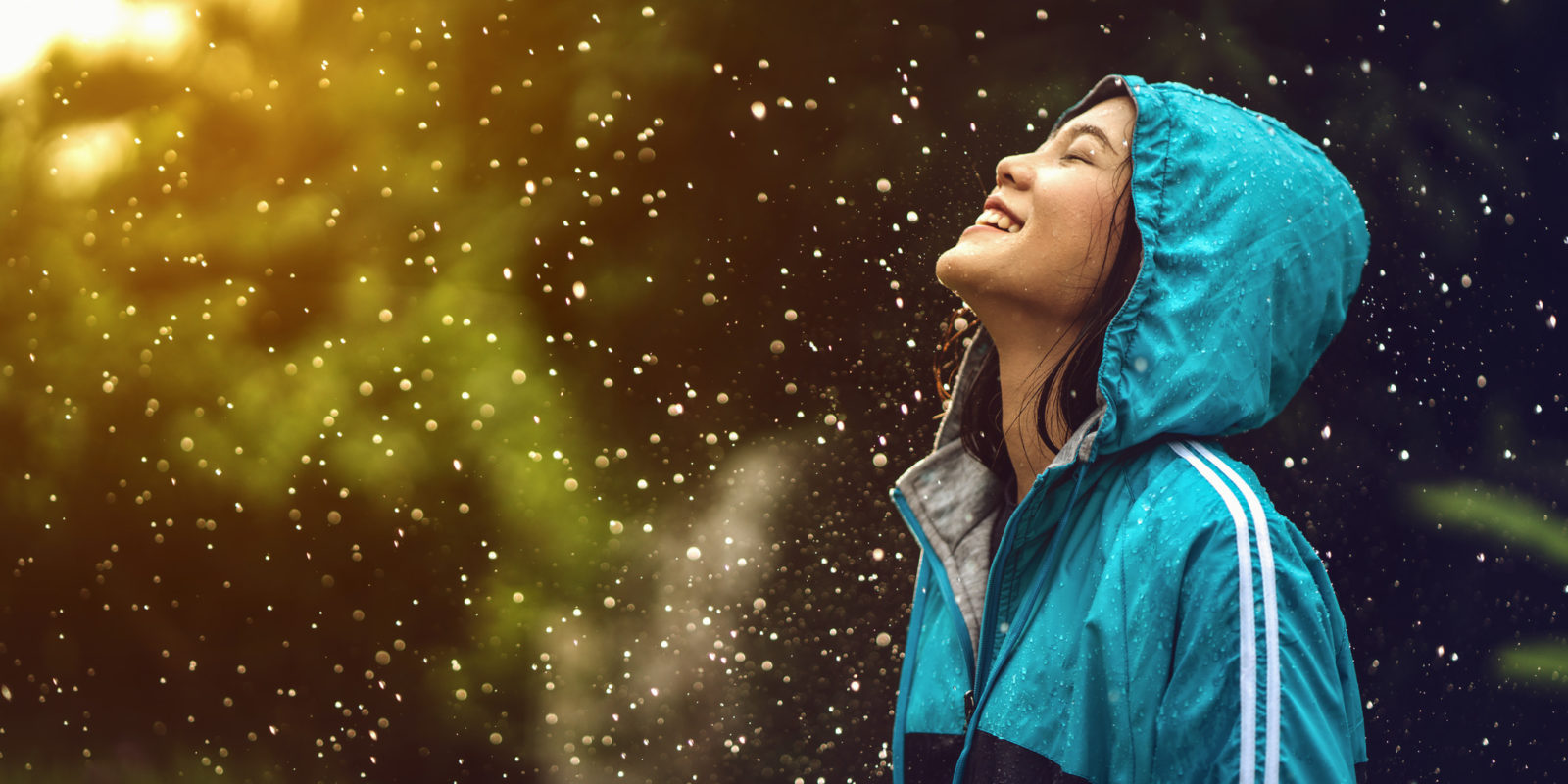 Asian woman wearing a raincoat outdoors. She is happy.